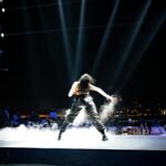 Female pop star performing on stage under bright lights representing Britney Spears concert performance